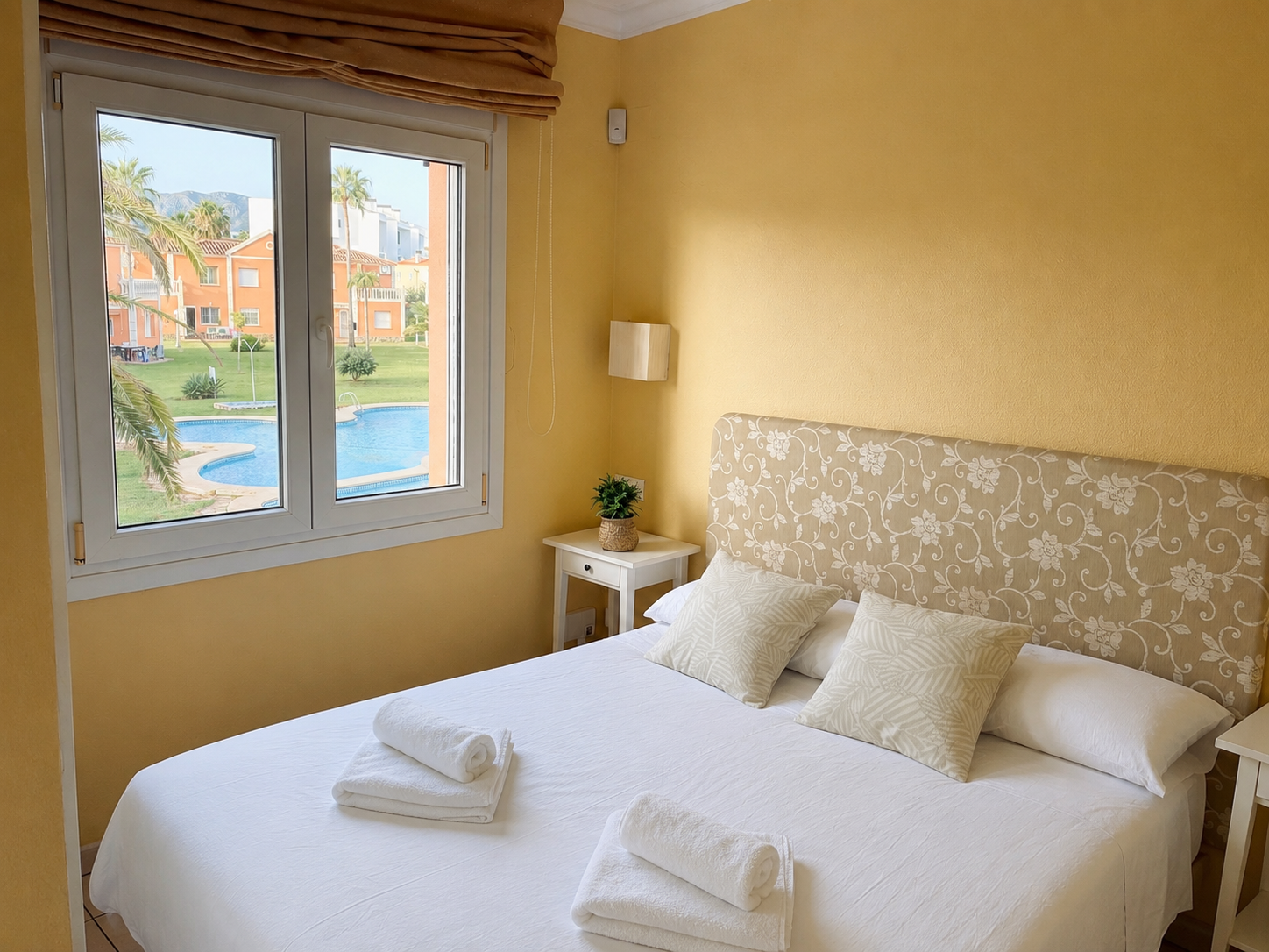 Dormitorio principal real con cama doble y vistas a la piscina